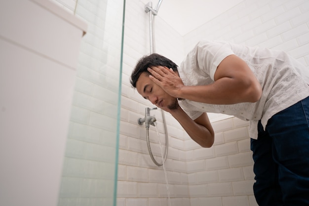 L'uomo musulmano pulisce il suo corpo con acqua di rubinetto prima di pregare. abluzione wudhu pulizia