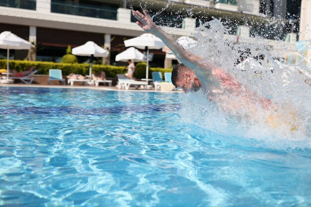 L'uomo nuota con un colpo al seno nella piscina blu di acqua limpida.
