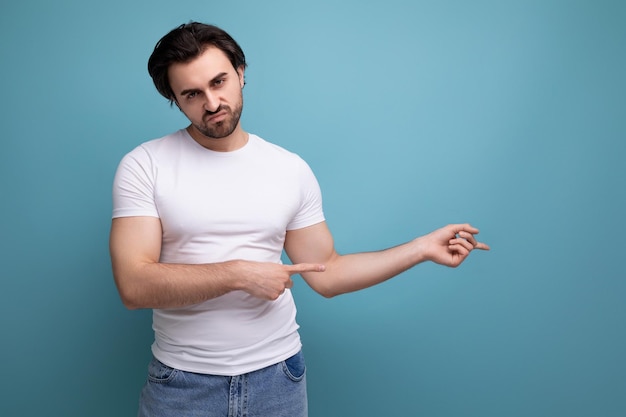 L'uomo pigro e stanco del brunette in una maglietta bianca e jeans punta un dito