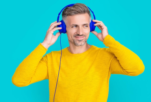 L'uomo positivo ascolta la musica nelle cuffie isolate sull'uomo blu ascolta la musica nelle cuffie