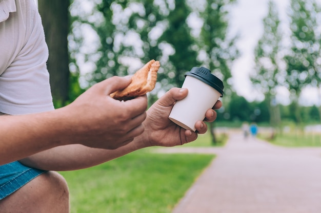 L'uomo pranza con un pane tostato con caffè in un bicchiere