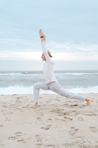 L'uomo pratica lo yoga sulla spiaggia del mare Gli adulti praticano lo yoga sulla spiaggia