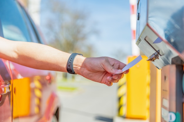 L'uomo prende un biglietto di parcheggio quando entra nel parcheggio a pagamento in auto