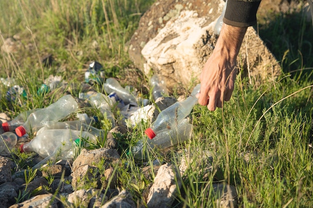 L'uomo prende una bottiglia di plastica dal parco in erba