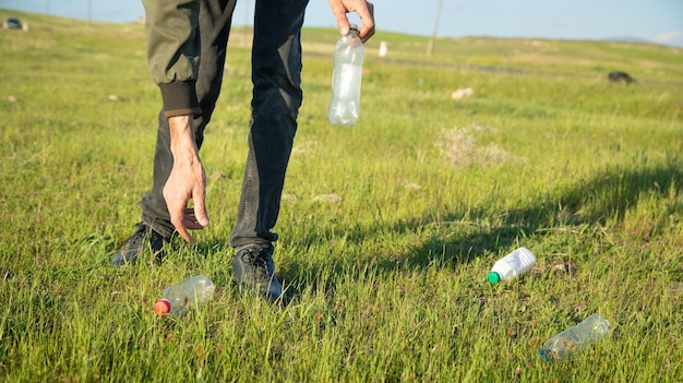 L'uomo prende una bottiglia di plastica dal parco in erba