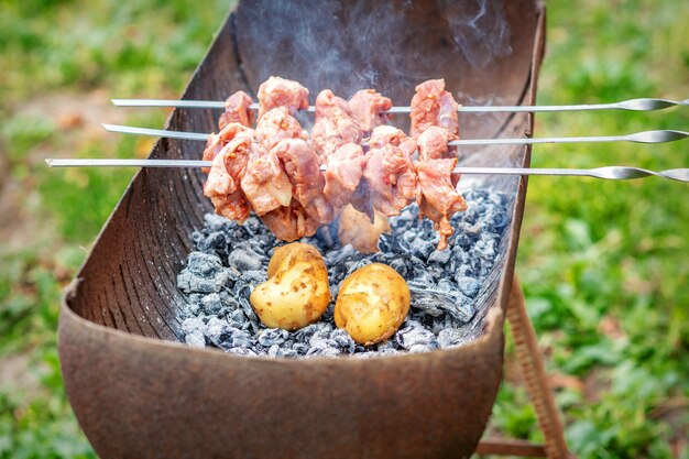 L'uomo prepara la carne barbecue con patate