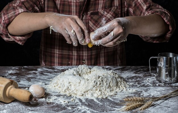 L&#39;uomo prepara pasta di pane sul tavolo di legno in una panetteria da vicino