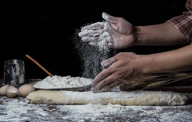 L&#39;uomo prepara pasta di pane sul tavolo di legno in una panetteria da vicino