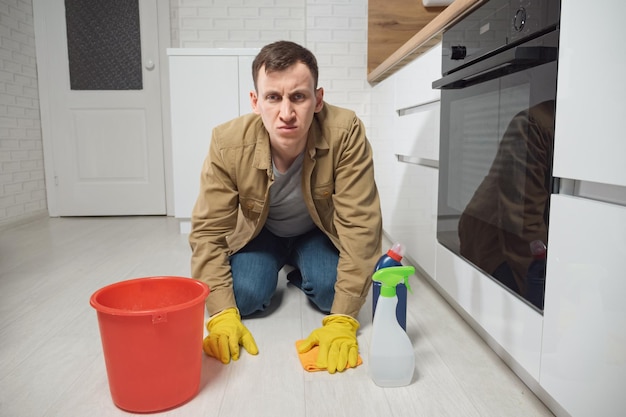 L'uomo pulisce il pavimento con detersivo e acqua in cucina