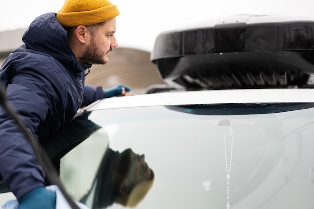 L'uomo pulisce il portapacchi per auto SUV americano con un panno in microfibra dopo il lavaggio a basse temperature