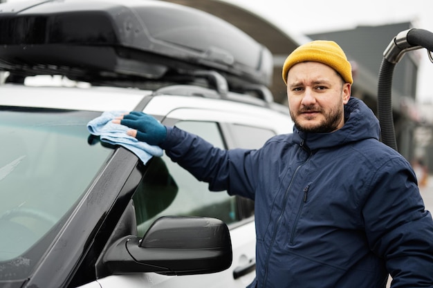 L'uomo pulisce l'auto SUV americana con un panno in microfibra dopo il lavaggio a basse temperature