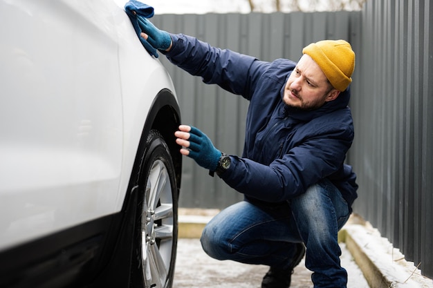 L'uomo pulisce l'auto SUV americana con un panno in microfibra dopo il lavaggio a basse temperature