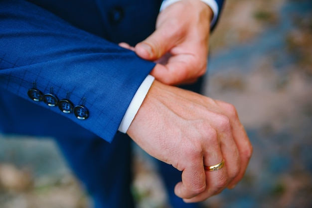 L'uomo raddrizza il polsino della giacca blu con il suo primo piano della mano