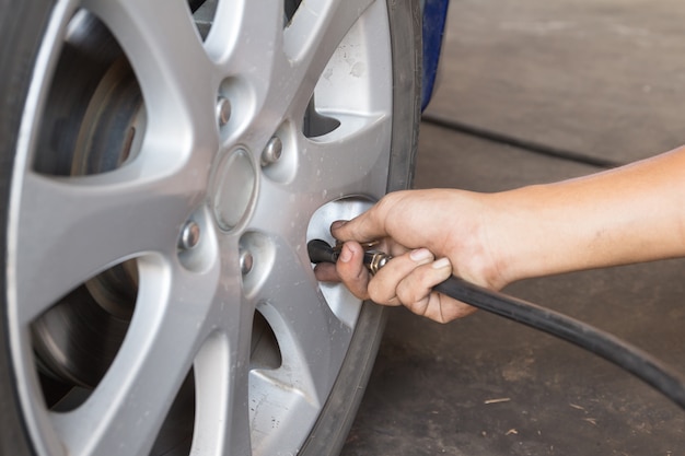 L'uomo riempie l'aria in un pneumatico per auto