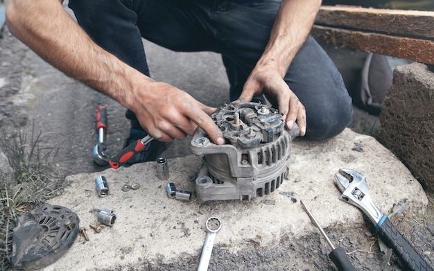 L'uomo ripara l'alternatore dell'auto. Centro Servizi