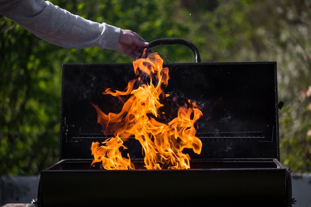 L'uomo riscalda il barbecue, preparando per grigliare alcuni tipi di carne