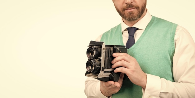 L'uomo ritagliato tiene la fotocamera retrò isolata su uno spazio di copia bianco che fotografa