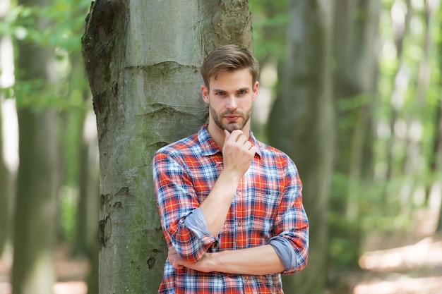 L'uomo serio ha i capelli ben curati sullo sfondo della foresta, barbiere.