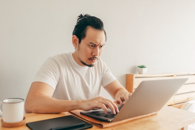 L'uomo serio sta lavorando nel suo appartamento