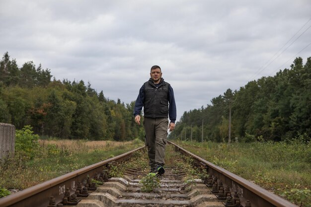 L'uomo si allontana sulla ferrovia con luce calda Ragazzo viaggiatore sulla ferrovia