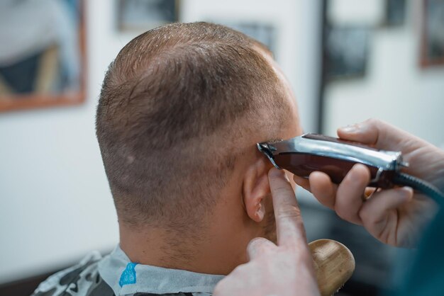 L'uomo si fa un bel taglio di capelli dal barbiere. Macchina da taglio da barbiere.