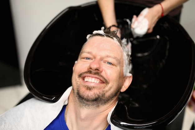 L'uomo si lava i capelli nel salone di bellezza dopo il taglio di capelli.