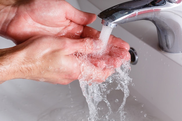 l'uomo si lava le mani vicino al lavabo bianco