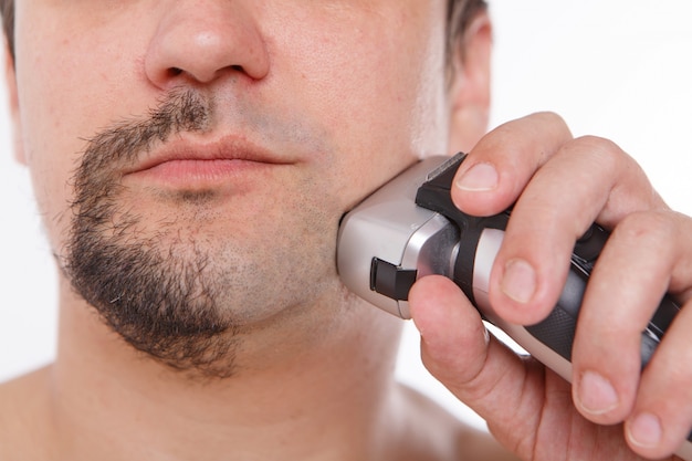 l'uomo si rade la barba. ragazzo si pulisce la barba con un rasoio elettrico. trattamenti mattutini in bagno.