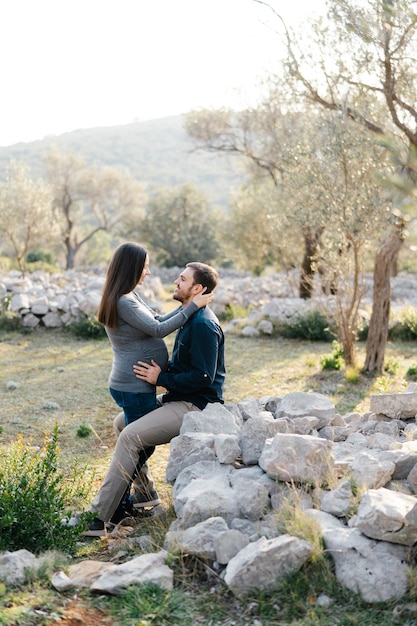 L'uomo si siede sulle pietre e tiene le mani sul ventre di una donna incinta