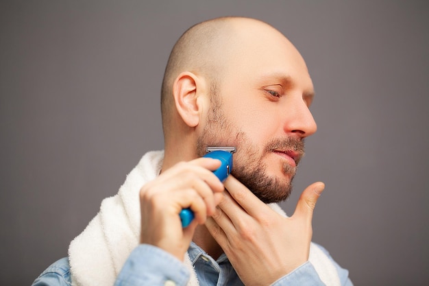 L'uomo si taglia la barba con una macchina da scrivere elettrica.