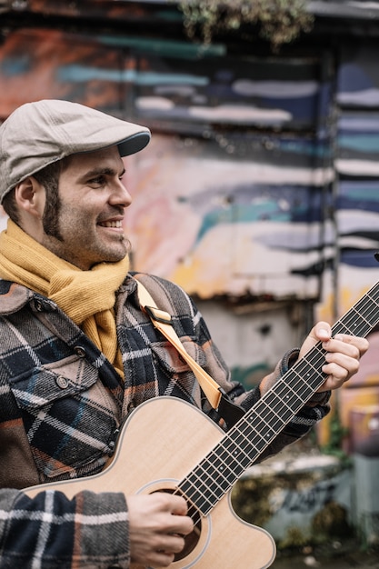 L'uomo si trova sulla strada e suona la chitarra acustica.