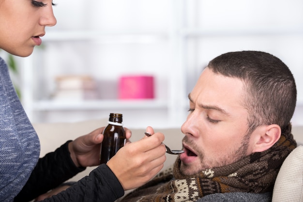 L'uomo soffre di freddo mentre la donna gli dà la medicina.