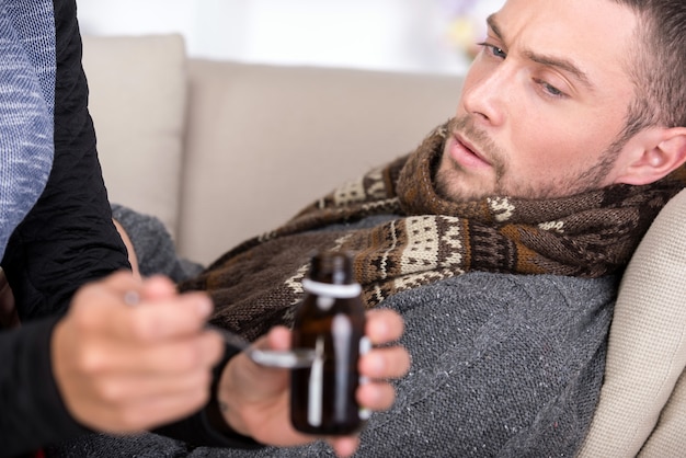 L&#39;uomo soffre di raffreddore. La donna gli dà la medicina.