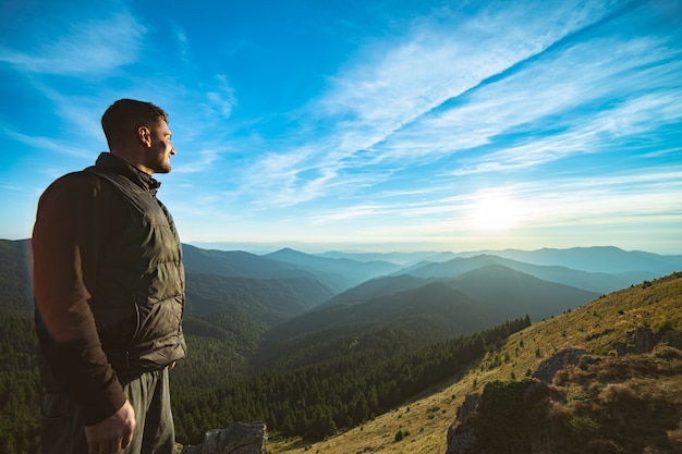 L'uomo sorridente in piedi sullo sfondo del bellissimo paesaggio di montagna