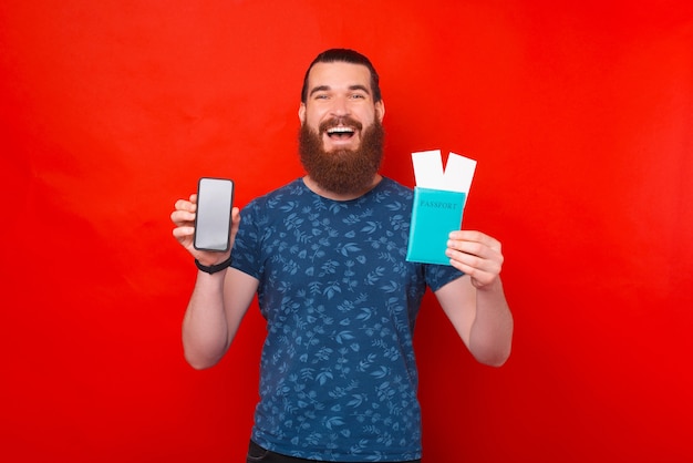 L'uomo sorridente tiene il passaporto con i biglietti e il suo telefono.