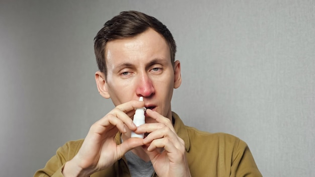 L'uomo spruzza farmaci nasali nelle narici per ottenere sollievo