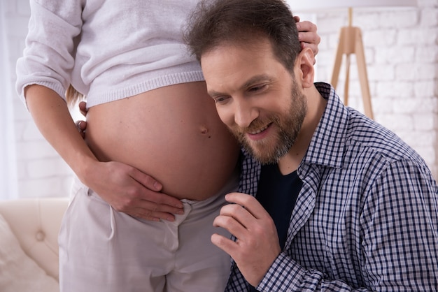 L&#39;uomo sta ascoltando la pancia incinta della sua donna