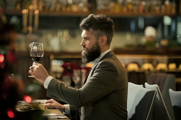 L'uomo sta assaggiando il vino Cena romantica giovane uomo in piedi e in possesso di bicchieri da vino