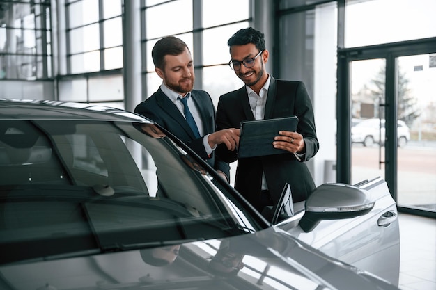 L'uomo sta consultando il cliente nello showroom dell'auto