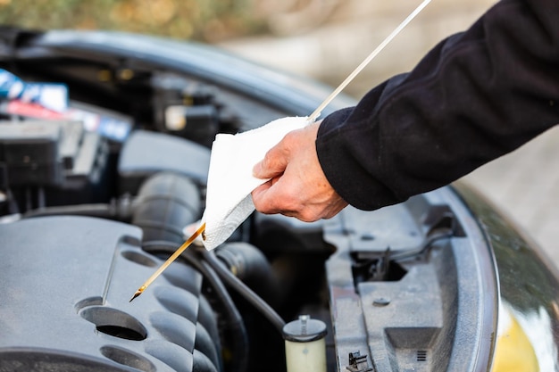 L'uomo sta controllando il livello dell'olio sull'auto.