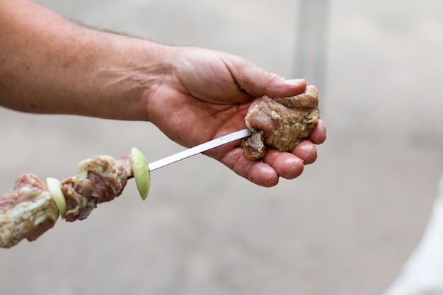 L'uomo sta cucinando shish kebab su uno spiedino