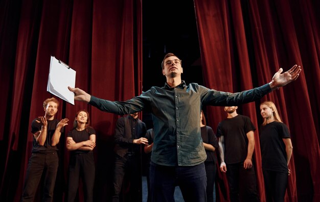 L'uomo sta esercitando il suo ruolo Gruppo di attori in abiti scuri durante le prove a teatro