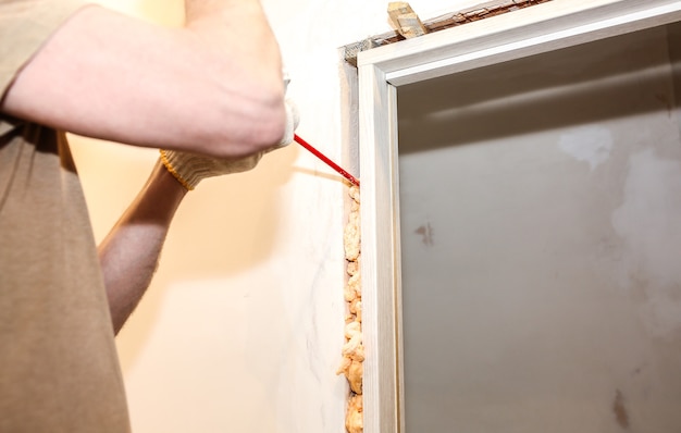 L'uomo sta installando la porta con una schiuma spray. Lavori di riparazione. Manutenzione in appartamento.