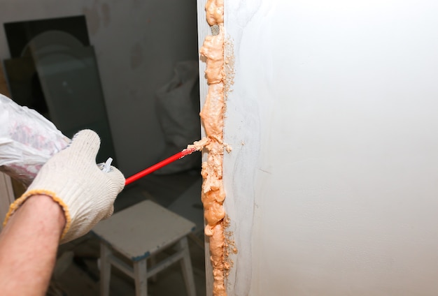 L'uomo sta installando la porta con una schiuma spray. Lavori di riparazione. Manutenzione in appartamento.