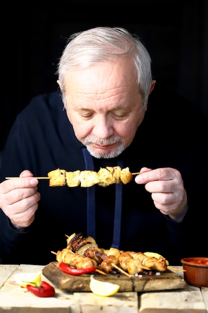 L'uomo sta mangiando uno spiedino di pollo