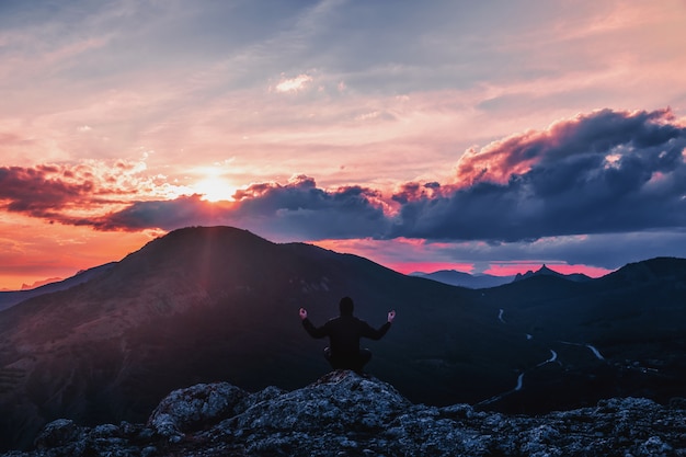 L'uomo sta meditando in montagna al tramonto.