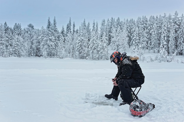 L'uomo sta pescando nel ghiaccio a Ruka in Lapponia, Finlandia