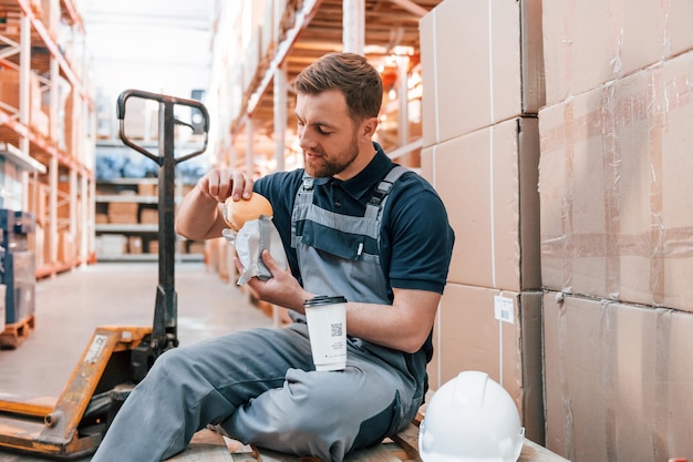 L'uomo sta pranzando Prendendo una pausa Il dipendente in uniforme lavora nel magazzino durante il giorno