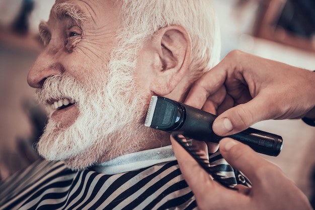 L&#39;uomo sta radendo il maschio adulto dai capelli grigio con il rasoio