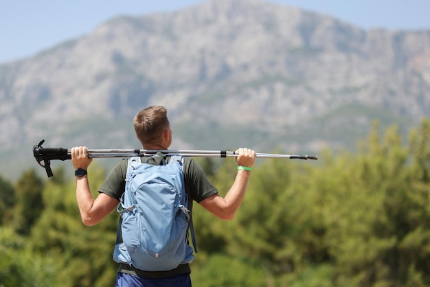 L'uomo sta sulla montagna e tiene i bastoncini da nordic walking che camminano nel concetto di montagna